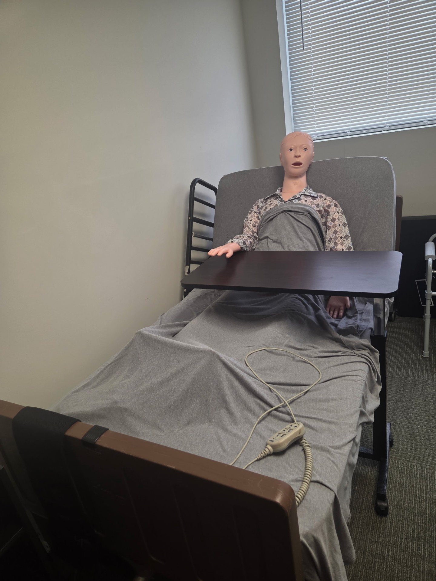 Training mannequin in adjustable hospital bed for caregiver practice